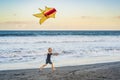 Happy young boy flying kite on the beach at sunset Royalty Free Stock Photo