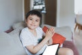 Happy young boy looking at camera with smiling face and clapping hands, Positive kid using tablet playing game online at home, Royalty Free Stock Photo