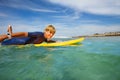 Happy young boy paddle on orange surfboard in ocean Royalty Free Stock Photo