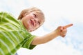 Happy young boy pointing at something. Low angle view of happy young boy standing against sky and pointing at something. Royalty Free Stock Photo