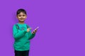 Happy young boy in shirt pointing up and holding arm white looking at the camera over isolated background and copy space