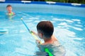 Happy young boys playing with water cannon in swimming pool