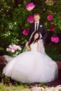 Happy young bride and groom in a pink decorated with peonies area in nature, family, relationships, romance, smiles, hugs, love Royalty Free Stock Photo