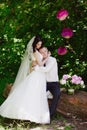 Happy young bride and groom in a pink decorated with peonies area in nature, family, relationships, romance, smiles, hugs, love Royalty Free Stock Photo