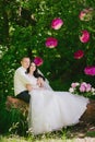 Happy young bride and groom in a pink decorated with peonies area in nature, family, relationships, romance, smiles, hugs, love Royalty Free Stock Photo