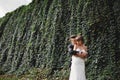 Happy young bride and groom on their wedding day. groom and bride hugging in front wall with green ivy Royalty Free Stock Photo