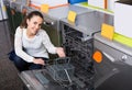 Happy brunette choosing new dish washing machine in appliance store Royalty Free Stock Photo