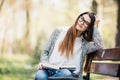Happy young brunette with a notebook in hands sitting on a park bench Royalty Free Stock Photo