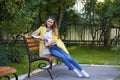 Happy young brunette sitting on a park bench Royalty Free Stock Photo