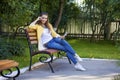 Happy young brunette sitting on a park bench Royalty Free Stock Photo