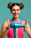 Happy young brunette woman hold green hair dryer smiling on blue mint background Royalty Free Stock Photo