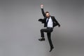 Happy young business man in classic black suit shirt tie posing on grey background. Achievement career wealth