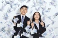 Happy young business man and woman hands pointing up and under money rain Royalty Free Stock Photo