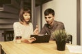 Happy young couple using digital tablet computer sitting at the table Royalty Free Stock Photo