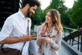 Happy young business people chatting and using digital devices together outdoors Royalty Free Stock Photo