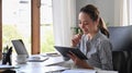 Happy business woman entrepreneur using digital tablet while working in internet at office desk. Royalty Free Stock Photo