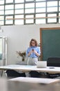 Happy young woman using cell phone standing in office at work. Royalty Free Stock Photo