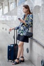 happy young business woman standing with hand luggage using mobile phone . traveling girl with suitcase and  smartphone in city Royalty Free Stock Photo