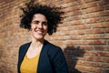 A happy young business woman standing outdoors, brick wall in the background. Royalty Free Stock Photo