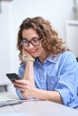 Happy young business woman using cell phone working in office, vertical. Royalty Free Stock Photo