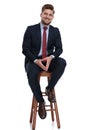 Happy young businessman holding hands and sitting on wooden chair