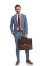 Happy young businessman in blue suit holding suitcase and smiling Royalty Free Stock Photo