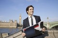 Happy young businessman with book standing against Big Ben clock tower, London, UK Royalty Free Stock Photo