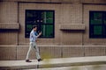 Happy Young Businessman in Casual wear Using or reading Mobile Phone while Walking by the Urban Building. Lifestyle of Modern Royalty Free Stock Photo