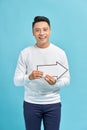 Happy young businessman holding a arrow pointing right and leaning against a wall isolated on blue background Royalty Free Stock Photo