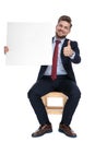 Happy young businessman holding board and making thumbs up sign Royalty Free Stock Photo