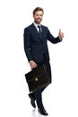 Happy young businessman holding suitcase and making thumbs up sign Royalty Free Stock Photo