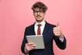 Happy young businessman holding tab and making thumbs up sign Royalty Free Stock Photo