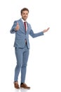 Happy young businessman making thumbs up gesture and presenting to side Royalty Free Stock Photo