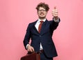 Happy young businessman making thumbs up sign and holding briefcase Royalty Free Stock Photo