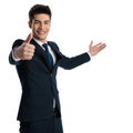 happy young businessman making thumbs up sign and showing to side Royalty Free Stock Photo