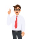 Happy young businessman showing/gesturing two, victory or v sign with hand fingers. Smiling man making peace sign. Positive human. Royalty Free Stock Photo