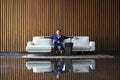 Happy young businessman sitting relaxed on sofa at hotel lobby using smartphon, waiting for someone. Royalty Free Stock Photo