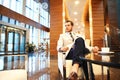 Happy young businessman sitting on sofa in hotel lobby Royalty Free Stock Photo