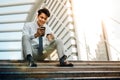 Happy Young Businessman Sitting on Staircase and Using Smartphone. Urban Lifestyle. Low Angle View