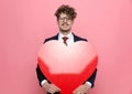 Happy young businessman in suit holding big red heart Royalty Free Stock Photo