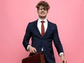Happy young businessman in suit holding suitcase and smiling Royalty Free Stock Photo