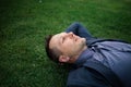 Happy Young businessman in a suit lying on the green grass and relaxing in park. Royalty Free Stock Photo