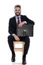 Happy young businessman in suit smiling and holding suitcase Royalty Free Stock Photo