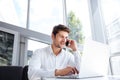 Happy young businessman talking on cell phone and using laptop Royalty Free Stock Photo