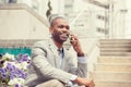 Happy young businessman talking on mobile phone sitting outdoors Royalty Free Stock Photo