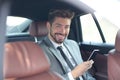 Happy young businessman using mobile phone in back seat of car Royalty Free Stock Photo