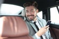 Happy young businessman using mobile phone in back seat of car Royalty Free Stock Photo