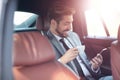 Happy young businessman using mobile phone in back seat of car Royalty Free Stock Photo