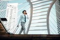 Happy Young Businessman Using Mobile Phone while Walking with Suitcase in the City. Lifestyle of Modern People. Low Angle View. Royalty Free Stock Photo