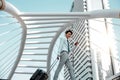 Happy Young Businessman Using Mobile Phone while Walking with Suitcase in the City. Lifestyle of Modern People. Low Angle View. Royalty Free Stock Photo